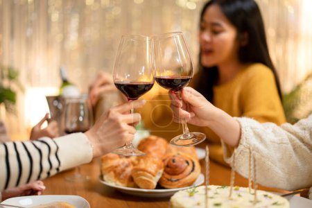 Téléchargez les photos : Jeune femme buvant et cliquetis verre de vin à griller avec bonheur tout en célébrant dans la fête du Nouvel An à la maison. - en image libre de droit
