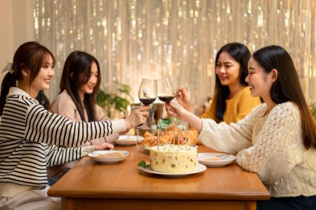 Téléchargez les photos : Jeune femme souriante boire et boire un verre de vin à griller avec bonheur tout en célébrant dans la fête du Nouvel An à la maison. - en image libre de droit