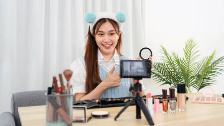 Photo for Young beauty influencer is showing powder product to testing and recommend cosmetic while recording video on camera for share on social media or web blogger in studio. - Royalty Free Image