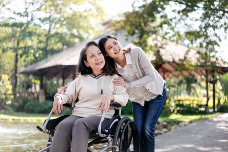 Foto de Familia feliz, Abuela anciana en silla de ruedas con hija sonriendo disfrutando en el jardín por la mañana. - Imagen libre de derechos