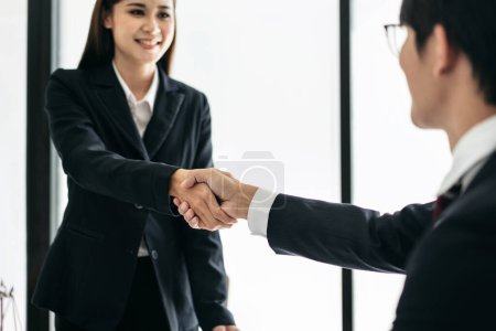 Photo for Male lawyer shaking hands with client after discussing deal of agreement together and signing contract on the table with brass scales and justice hammer in law firm. - Royalty Free Image