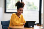 African american student woman in sweater using digital tablet to watching e-learning and studying lesson online class while sitting on the desk to learning knowledge and education in university. Poster #646177514