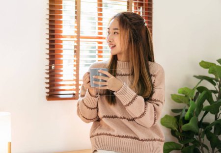 Foto de Mujer bebiendo chocolate caliente para disfrutar de ensueño y relajarse con la mirada al aire libre, mientras que el ocio con un estilo de vida acogedor en la sala de estar en casa. - Imagen libre de derechos