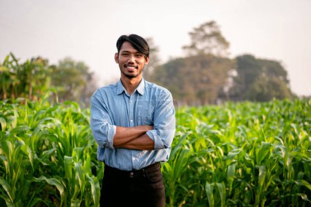 Photo for Smart farmer smiling and standing with arms cross in corn field after examining quality crop of corn vegetables while working and planning system control with technology at agricultural field. - Royalty Free Image