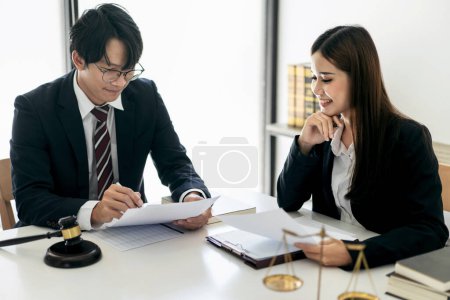 Photo for Female lawyer is discussing and legal advice about business contract to client while businessman holding to pointing on document and asking about laws and agreements of contracts in law firm office. - Royalty Free Image