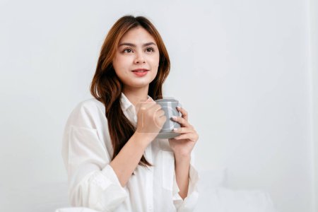 Photo for Activity at home leisure lifestyle concept, Young woman in clothes casual drinking hot chocolate with enjoying while sitting on comfy bed to leisure with lifestyle at home. - Royalty Free Image
