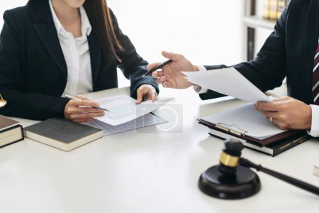 Female lawyer holding business document to reading contract and businessman explaining detail on document to asking about laws and agreements of contracts in law firm office.