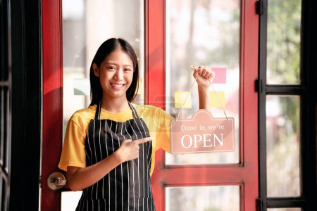 Photo for Small business with coffee shop and restaurant open concept, Female entrepreneur standing near cafe entrance and pointing open sign to ready for service coffee and food for customer in restaurant. - Royalty Free Image
