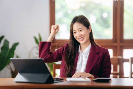 Accounting business concept, Accountant woman excited and raising fist to celebrate achievement while working on laptop about investment with business planning finance.