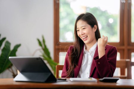 Accounting business concept, Accountant woman excited and raising fist to celebrate achievement while working on laptop about investment with business planning finance.
