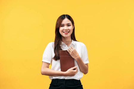 Photo for Young asian woman wearing white short sleeve shirt and holds holy bible to learning and praying to god about spirituality faith worship isolated over yellow background. - Royalty Free Image