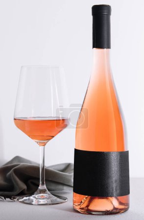 Glas und Flasche Rosenwein auf hellem Hintergrund