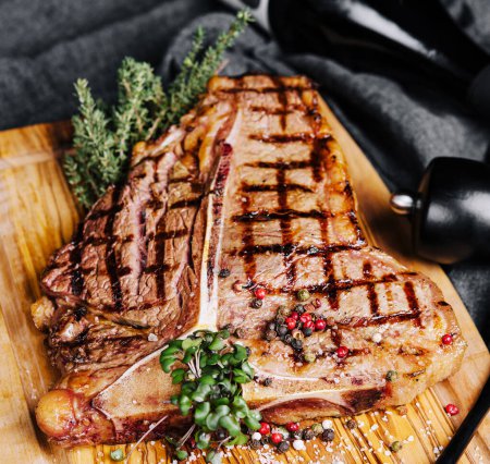 Téléchargez les photos : Un gros steak grillé sur une assiette en bois - en image libre de droit
