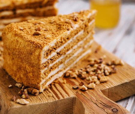 Téléchargez les photos : Slice of sweet honey cake on wooden board - en image libre de droit