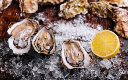 Foto de Opened oysters, ice and lemon on board - Imagen libre de derechos