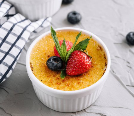cup of creme brulee with dessert plug and mint leave with berries