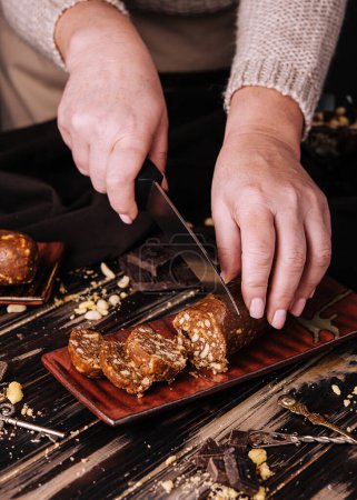 Foto de Woman cuts chocolate potato dessert with a knife - Imagen libre de derechos