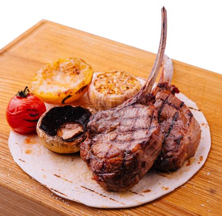 Grilled lamb chops on wooden board with herbs and spices