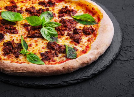 Pizza con carne picada y mozzarella en una tabla de piedra
