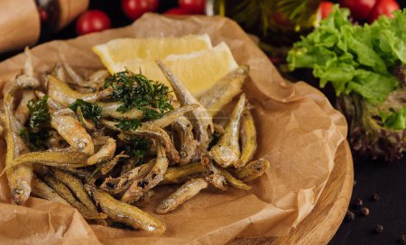 Hot fried smelt fish with salt and herbs on brown paper