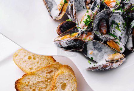 Plate of tasty mussels with parsley and toasted bread