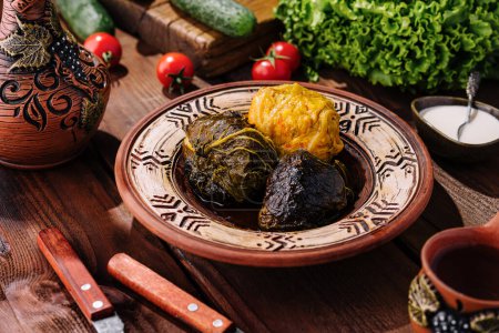 Dolma - seasoned rice wrapped in grape leaves, served on handcrafted plate with fresh vegetables