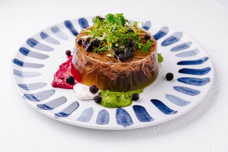 Elegant gelatin dessert with berries and microgreens served on a striped plate against a white background