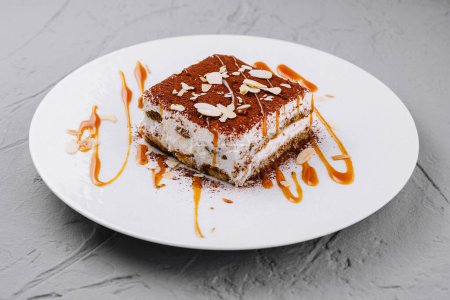Elegant tiramisu dessert artfully plated with almond slices and caramel sauce