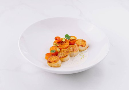 Gourmet seared scallops with herbs and garnish served on a sleek white dish