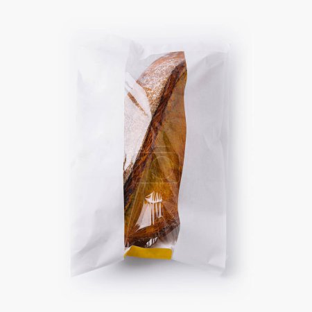 Fresh loaf of bread partially wrapped in a paper bag, isolated on a white backdrop