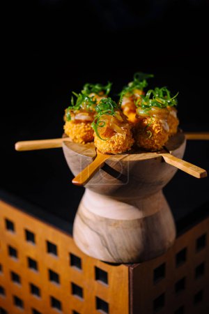 Künstlerische Präsentation einzigartiger Sushi-Pops garniert mit grünen Zwiebeln auf einem stilvollen Holzserver