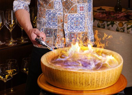 Chef preparing pasta in a flaming cheese wheel at a gourmet restaurant
