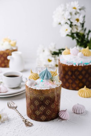 Traditional easter kulich topped with pastel frosting and merengues, served with tea