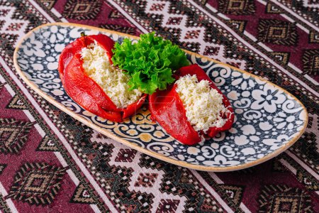Foto de Deliciosos pimientos rojos llenos de queso en un plato con dibujos, cocina tradicional - Imagen libre de derechos
