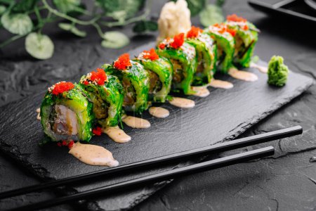 Delectable sushi roll topped with tobiko and spicy mayo on a dark slate