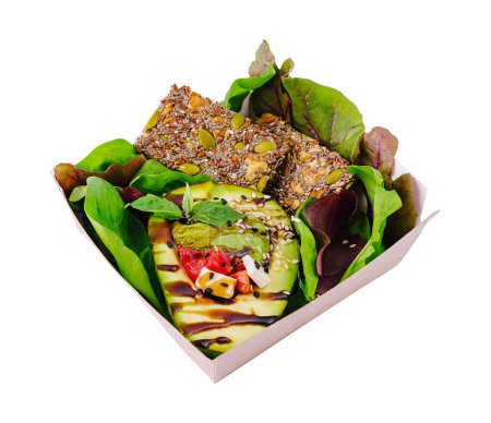 Nutritious vegan meal featuring avocado, mixed greens, and seed bars in a takeout box