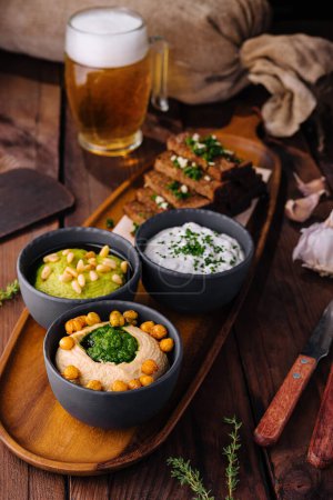 Photo for Appetizing selection of beer snacks with toasts and various dips on a rustic wooden serving board - Royalty Free Image