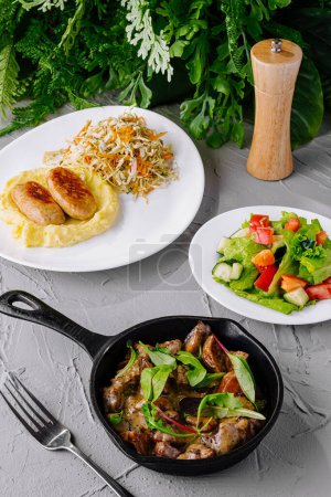 Foto de Variedad de platos saludables, incluyendo ensalada, puré de papas y una sartén de carne - Imagen libre de derechos