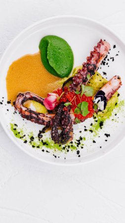 Elegantes Gericht aus gegrilltem Oktopus mit bunten Gemüsepürees und Gewürzen