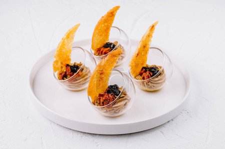 Platter of sophisticated appetizers with crispy wafers served on a sleek white background