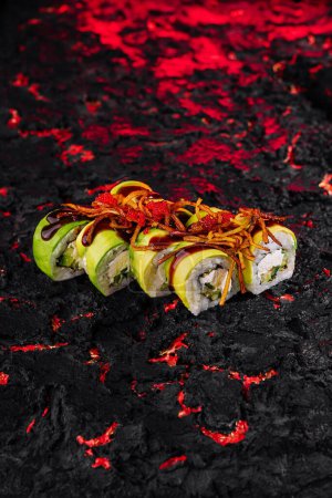 Rouleau de sushi à l'avocat vibrant surmonté d'une sauce épicée sur un fond texturé rouge et noir flamboyant