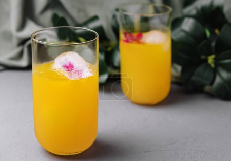 Elegante orangefarbene Getränke mit essbaren Blüten in Eis, perfekt für Sommerveranstaltungen