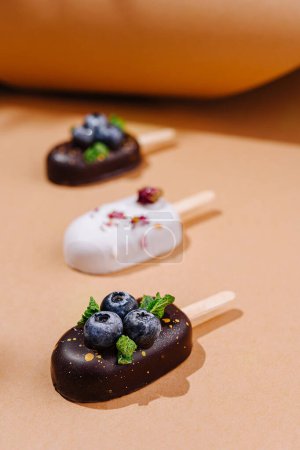 Handgemachte Eiscreme mit frischen Blaubeeren und Schokolade auf warmem, neutralem Hintergrund