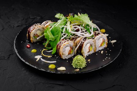 Beautifully presented sushi roll selection with garnishes on a modern black plate