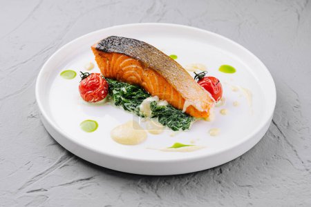 Elegant presentation of grilled salmon on a bed of spinach with roasted cherry tomatoes