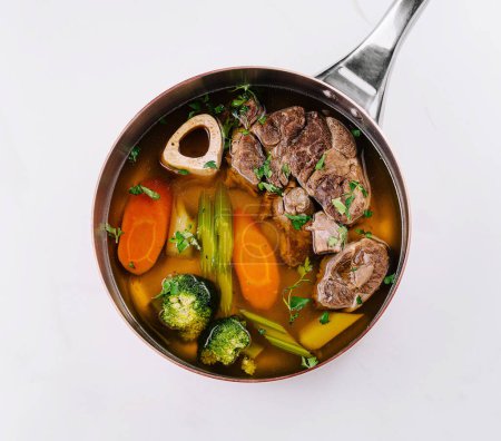 Top view of a delicious beef soup with vegetables in a pot, ready to serve