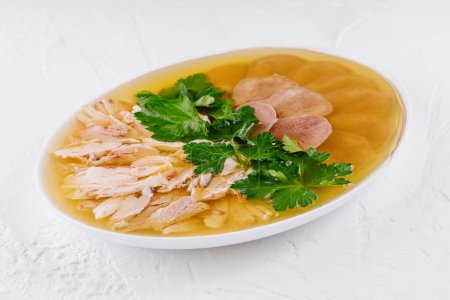 Nutritious chicken aspic with shredded chicken, fresh parsley and bread served in a white bowl