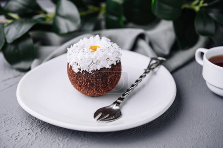 Exquisites Kokos-Dessert auf einem weißen Teller, garniert mit Kokosflocken, gepaart mit einem Tee-Set