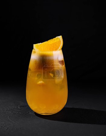 Close-up of a chilled orange cocktail garnished with a slice and served in a stylish glass