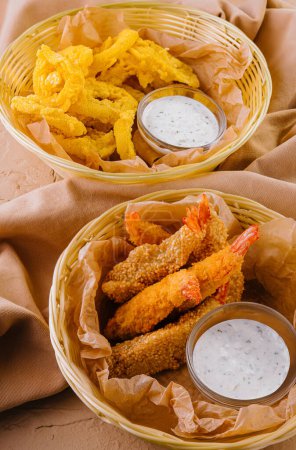 Delectable arrangement of crispy fried shrimp with tartar sauce and golden chips in wicker baskets